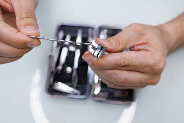 Pulls nail clippers out of the manicure kit. A man gives himself a manicure
