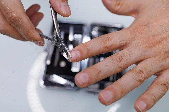 Using special clippers to trim the nails. A man gives himself a manicure