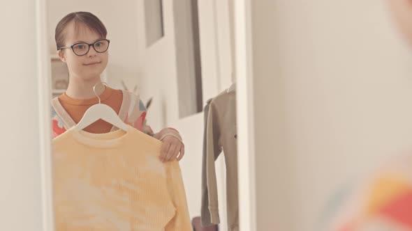 Girl with Down Syndrome Choosing Outfit in front of Mirror alt