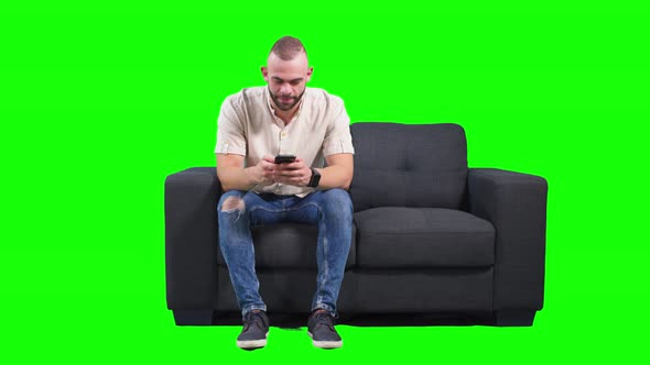 Man Typing Text Message on Smartphone and Laughing Green Background