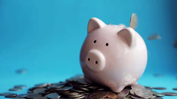 Man Putting Coins in Piggy Bank of Pig Shape in Pile of Coins, Hand Closeup. alt