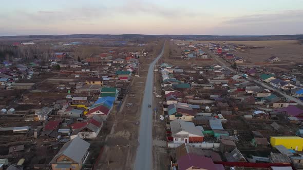 Aerial view of Spring evening in the village. Car are driving along the road alt