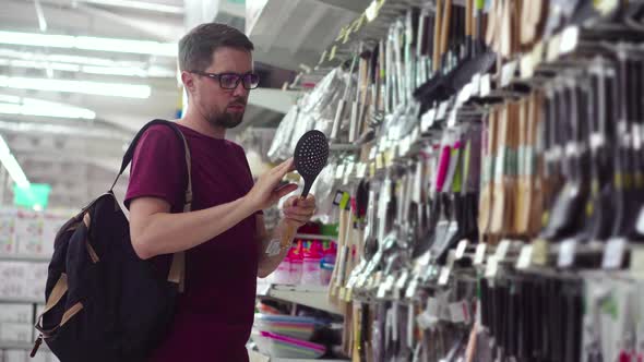 Young Male is Buying Kitchen Utensils in a Hypermarket alt