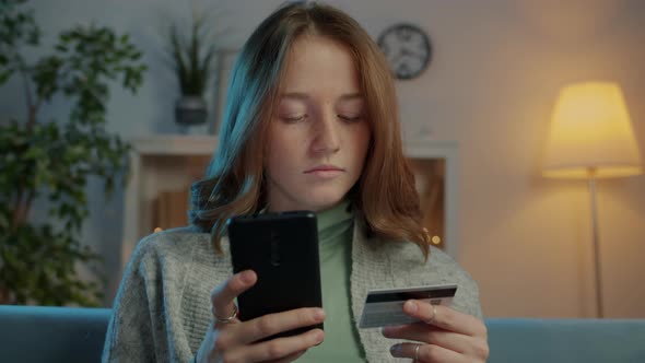 Cute Girl Shopaholic Paying Online with Smartphone Using Credit Card Smiling in Evening alt