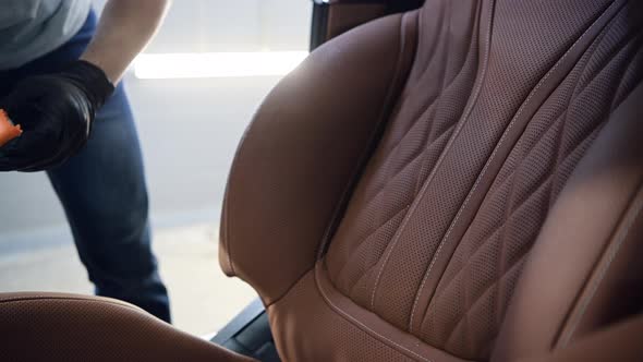 Man Spraying Cleaning Liquid and Wipe Passenger Front Seat in Luxury Car