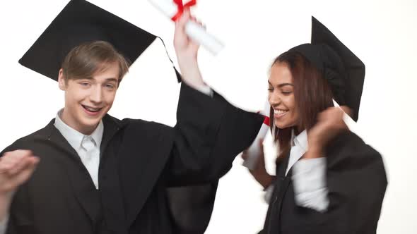 Caucasian Young Graduate Male Happily Dancing and Rejoicing with African American Female in Black alt