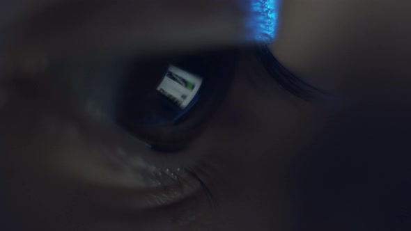 Macro view of laptop screen reflection in brown human eye. Surfing internet social media. Night work