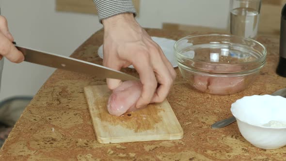  Man's Hands Cutting a Chicken Meat on a Wood Board on the Table