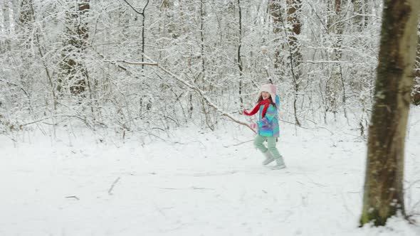 Child Girl in a Colorful Clothing Running in a Snowy Winter Park