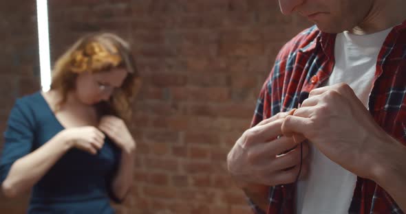 Male and Female Bloggers Adjusting Small Lavalier Microphone on Clothes Before Filming Video alt