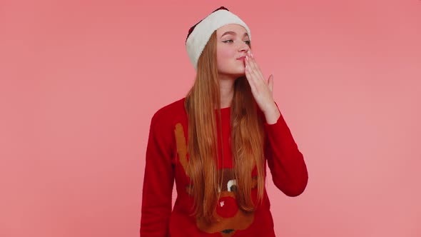 Girl in Christmas Sweater Sending Lots of Air Kisses Looking at Camera and Smiling Missing you Love alt