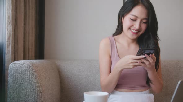 cheerful female Asian client entering payment information in shopping application
