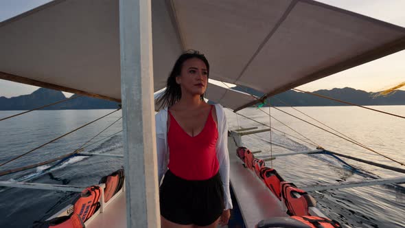 Woman Walking Along Deck Of Boat To Look Out Over Sea alt