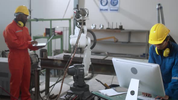 asian engineer technician control manage robot arm welding automation with computer monitor screen