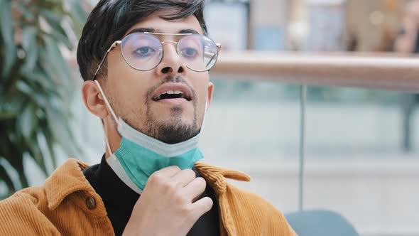 Closeup Young Hispanic Guy Takes Off Protective Medical Mask Breathes Fresh Air Taking Deep Breath alt