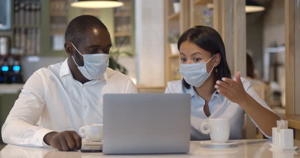 Business People Wearing Face Mask Working Together on Laptop in Modern Restaurant alt