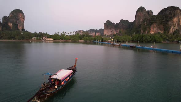 Thai longtail boat arriving at the docks in Railay Beach of Krabi Thailand during sunrise with large alt