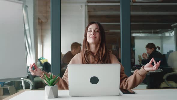 Tired Calm Beautiful Millennial Woman with Sweatshirt Sit at Work Desk Do Yoga Exercise Take Break alt