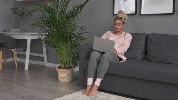 Young Business Woman Working on Laptop on Sofa at Home