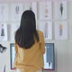 Back View Of Female Designer With Sewing Machine Look At The Pictures On The Wall While Designing - VideoHive Item for Sale