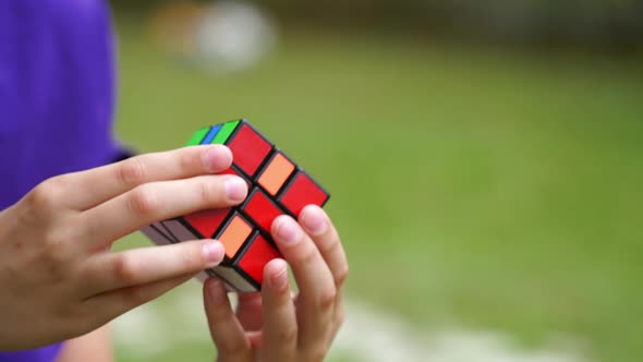 Close-up of rubik's cube in boy's hands. Boy is holding rubik cube and solving puzzle alt