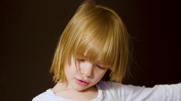 Studio portrait of a cute little blonde girl looking sad alt