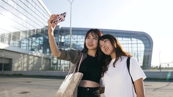 Exuberant Cute Asian Female Mates Making Selfie on the Airport Background alt