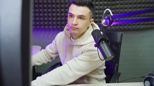 Serious Professional Radio Host Broadcasts Live Reads News on Computer Screen alt