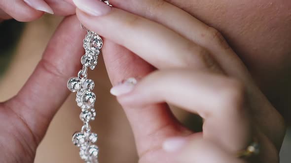 Woman with Manicure Puts on Earring with Gems Closeup alt