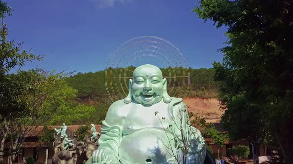 Camera Moves To Giant Merry Buddha Statue Against Hills alt