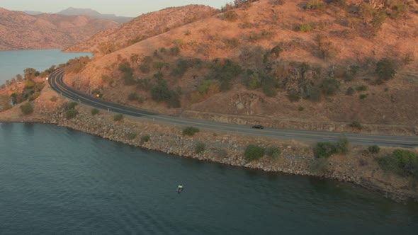 Aerial Drone Tracking Shot of a Car Driving next to a Lake During Sunset (Lake Kaweah, Visalia, CA)