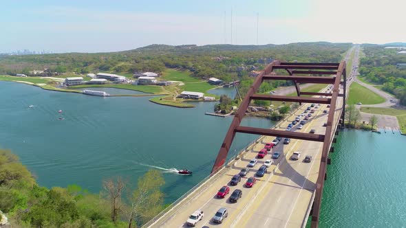 Bumper to bumper car traffic on the Pennybacker bridge with a view of Austin, Texas in the upper lef alt