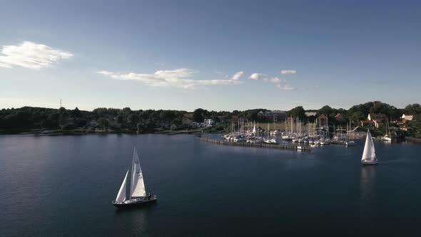 Flying Slowly Around A Sailboat With Harbor And Another Sailboat In Background Trip Ends In Sunset