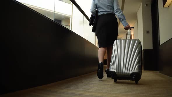 Female with Suitcase Walking Along Hotel Corridor alt