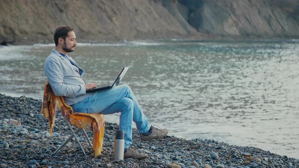 Man or Millennial Freelancer Write Blog Post or Work on Remote Office Project on Laptop While Coast alt