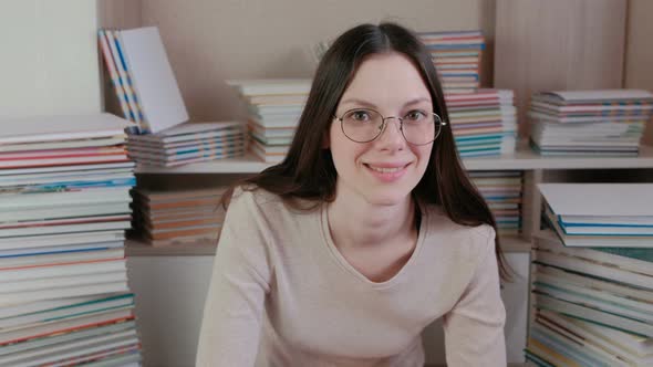 Young Brunette Woman in Glasses Is Thinking and Smiling