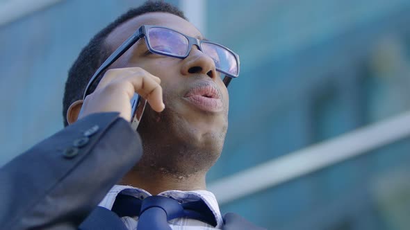 Handsome busy black american manager talking by phone in the city alt