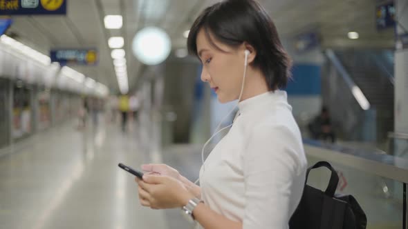 Portrait of asian woman with earphone listening music and using smartphone