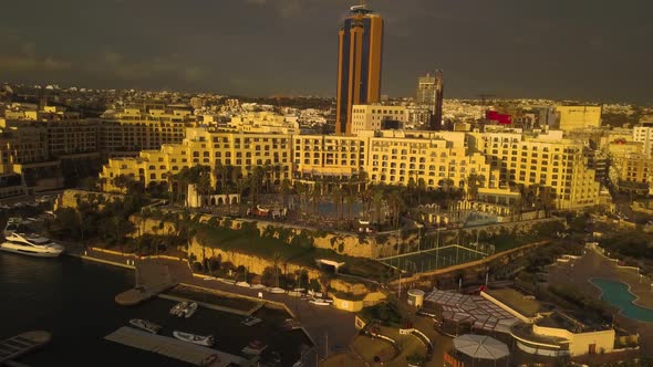 Aerial view of San Giljan, Malta at sunrise as the morning light makes the whole city glow with a go alt
