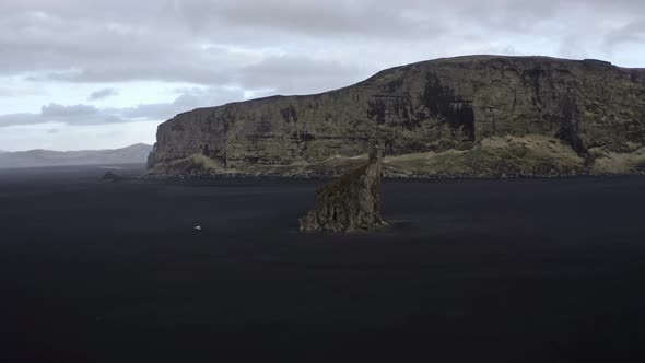Aerial Shot of Sea Stack and Tall Cliff Seen in the Background alt