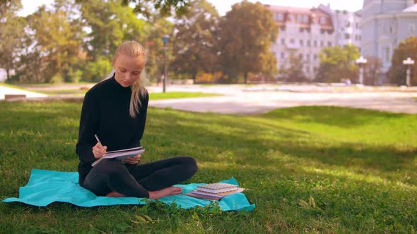 Girl Blonde Writing in Notebook Outdoors alt