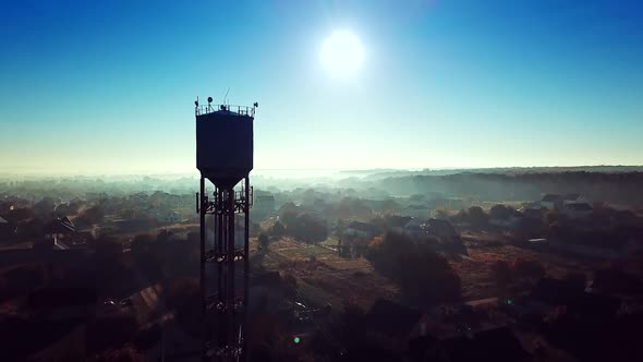 Flying over the village near the power station tower on a blue background sunrise. alt