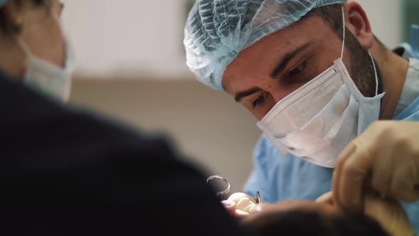 a man surgeon performs face and hands surgery close-up alt