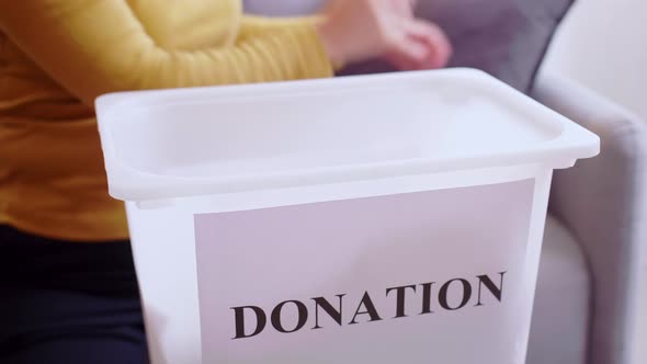 Woman selecting clothes for donation. Clothing donations concept. alt