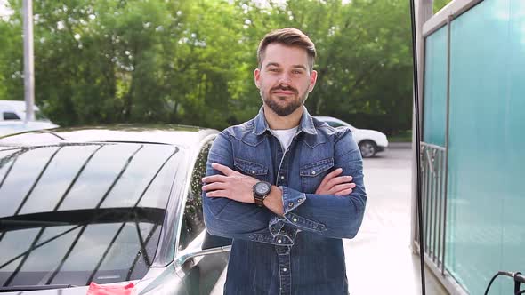 Young Bearded Guy Standing Near His Luxurious Freshly Washed Car in Outdoors Car Wash alt