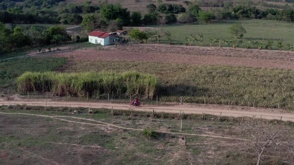 Aerial shot following a motorbike driving through dirt roads in the countryside of Brazil. alt