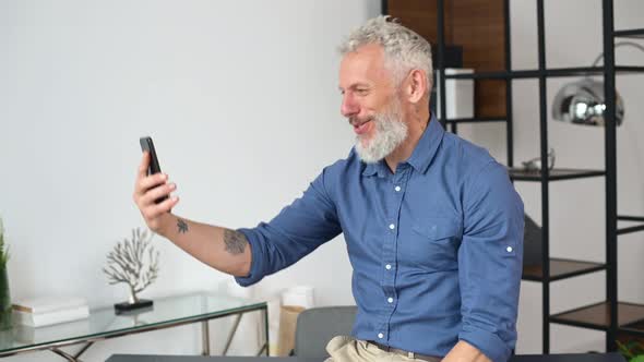 Happy Senior Businessman in Casual Wear Making Video Call on the Smartphone alt