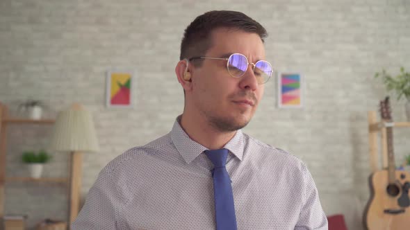 Portrait of a Hard of Hearing Man with a Hearing Aid in His Ear in the Living Room alt
