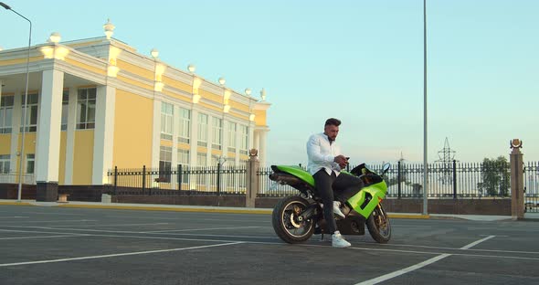 Man Sitting on Motorcycle and Using Smartphone in City