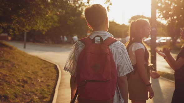 A Boy with a Backpack Walks Down the Street at Sunrise